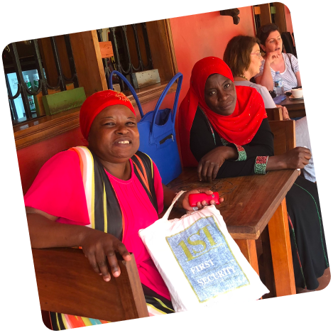 Two AfriBead women artisans seated at a table, smiling for a photo.