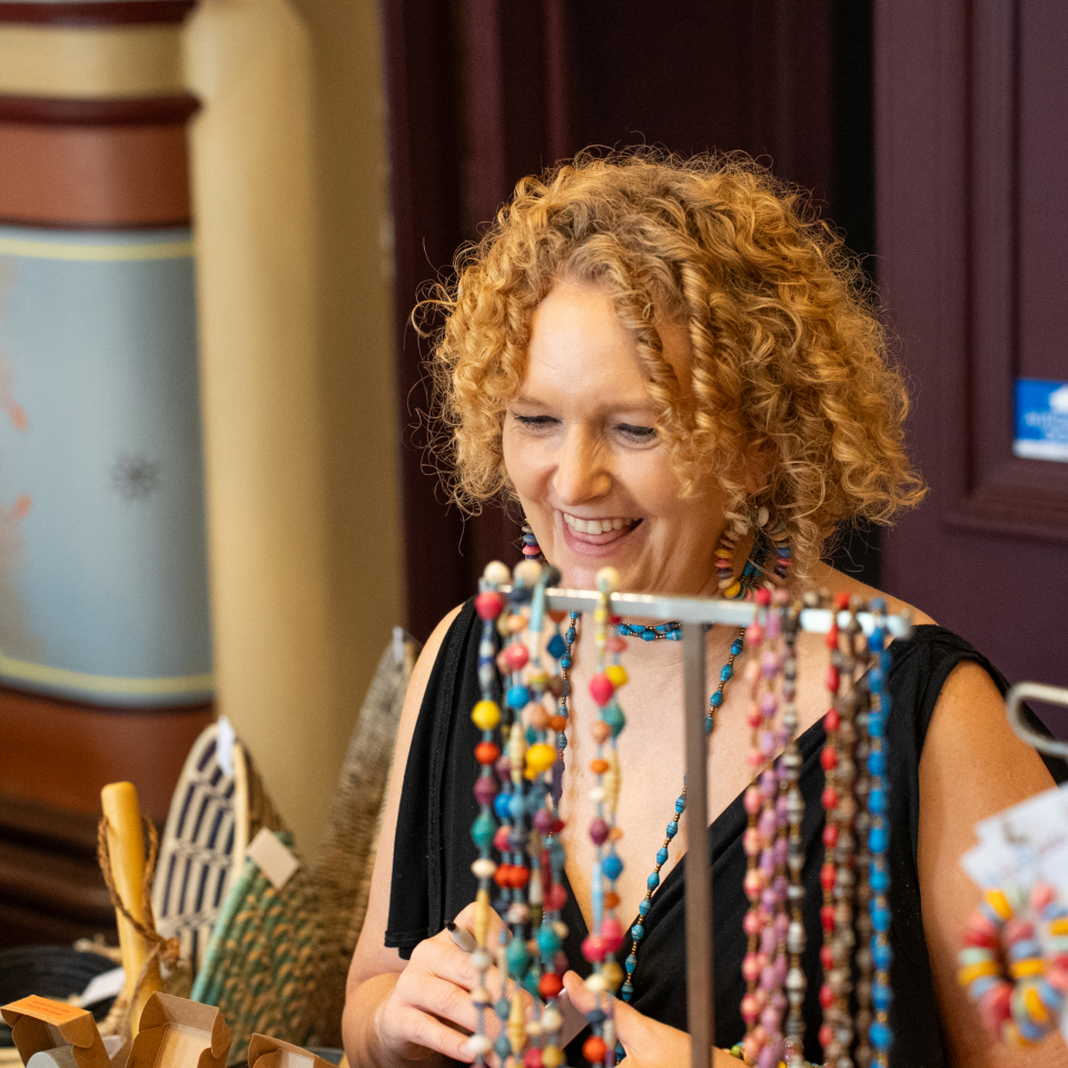 Nimmity at an AfriBeads market stall, standing behind a display of paper bead jewellery